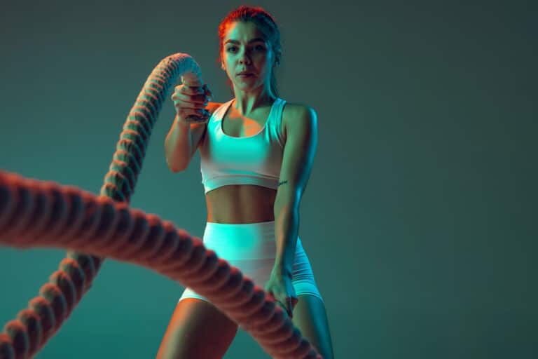 portrait young spotive girl doing exercises with rope keeping body fit isolated green background neon