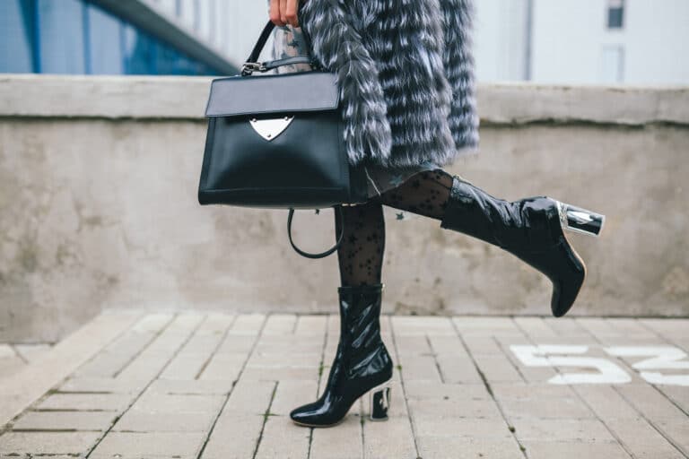 close up accessories details stylish woman walking city warm fur coat winter season cold weather holding leather handbag legs boots footwear street fashion trend